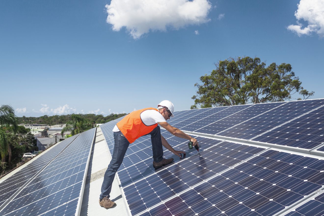 Man fixing solar panels to a roof