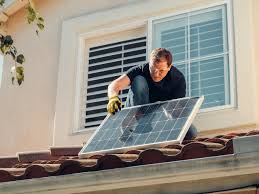 Man on a roof doing DIY home solar panel installation.