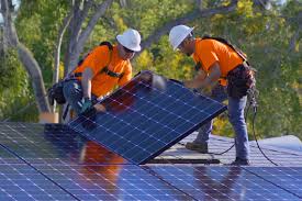 Two men in protective safety equipment installing solar panels.